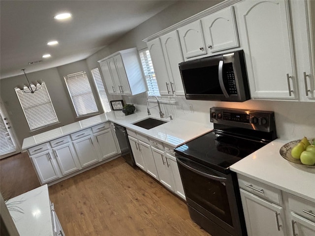 kitchen with sink, wood-type flooring, black appliances, and white cabinets