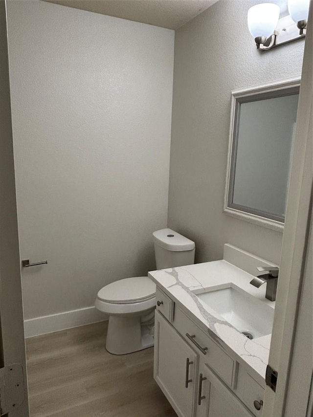 bathroom with wood-type flooring, toilet, and vanity