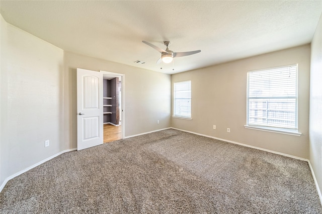 empty room with ceiling fan, carpet floors, and a textured ceiling