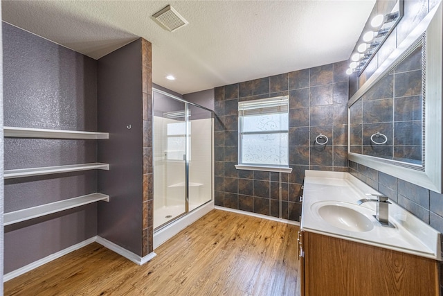 bathroom featuring hardwood / wood-style flooring, vanity, a textured ceiling, and a shower with shower door