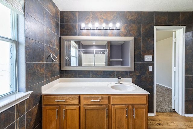 bathroom with vanity, wood-type flooring, and tile walls