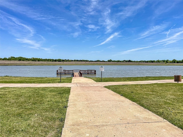 view of dock with a water view and a yard