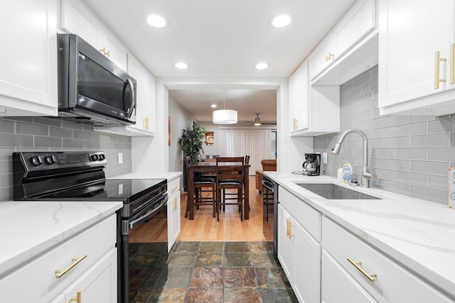 kitchen featuring white cabinetry, sink, light stone counters, pendant lighting, and black appliances