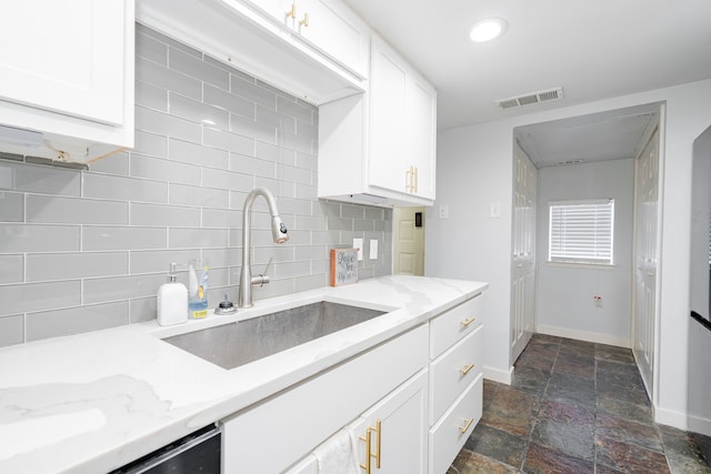 kitchen featuring white cabinets, sink, stainless steel dishwasher, tasteful backsplash, and light stone counters