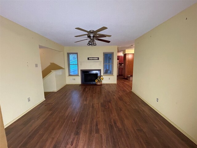 unfurnished living room featuring ceiling fan, dark hardwood / wood-style flooring, and a textured ceiling