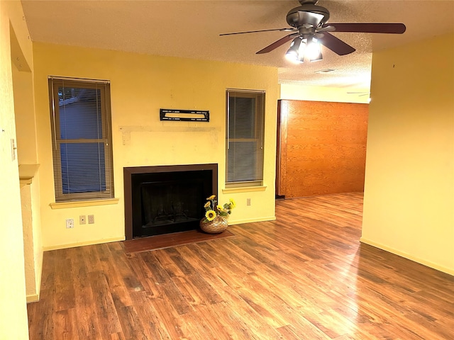 unfurnished living room featuring ceiling fan, hardwood / wood-style floors, and a textured ceiling