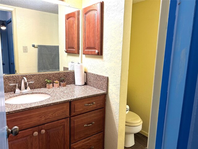 bathroom with vanity, toilet, and a textured ceiling