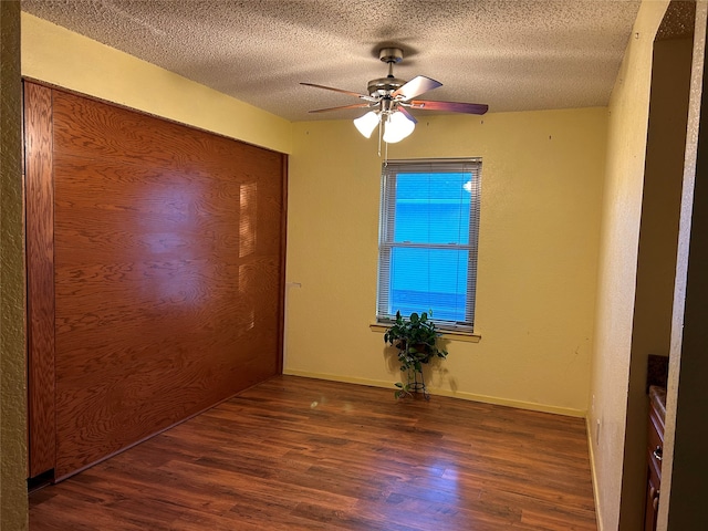 unfurnished room with ceiling fan, dark hardwood / wood-style flooring, and a textured ceiling