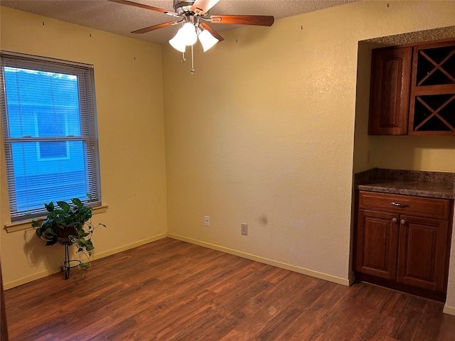 empty room with ceiling fan, dark hardwood / wood-style flooring, and a textured ceiling