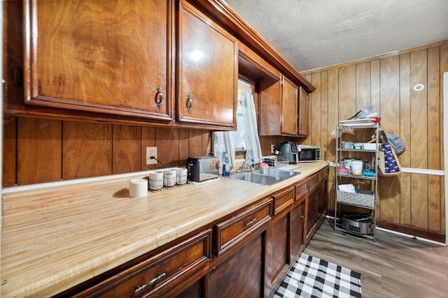 kitchen featuring sink, a textured ceiling, dark hardwood / wood-style flooring, and wood walls