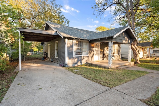 bungalow-style home featuring a front lawn, a porch, and a carport