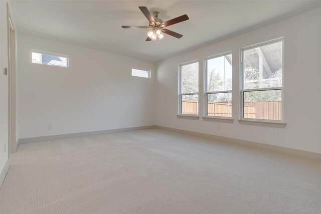 spare room featuring plenty of natural light, light colored carpet, and ceiling fan