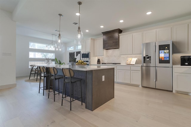 kitchen featuring a breakfast bar, white cabinetry, a kitchen island, stainless steel fridge with ice dispenser, and decorative light fixtures