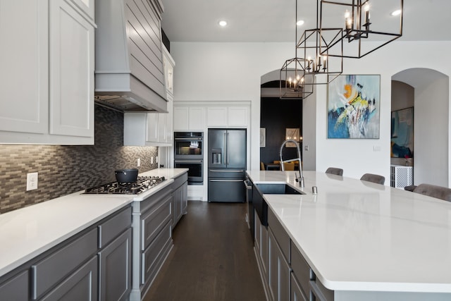 2608 Camden Ct, Celina, TX 75009 - kitchen with appliances with stainless steel finishes, a sink, custom range hood, arched walkways, and a chandelier