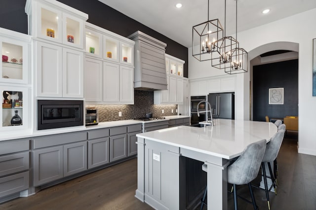 2608 Camden Ct, Celina, TX 75009 - kitchen featuring black appliances, gray cabinets, arched walkways, dark wood finished floors, and tasteful backsplash