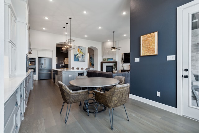 2608 Camden Ct, Celina, TX 75009 - dining space with a glass covered fireplace, a ceiling fan, dark wood-style flooring, arched walkways, and recessed lighting