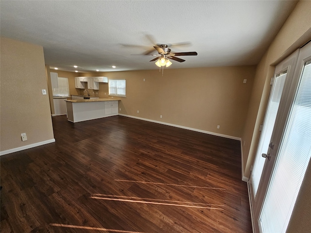 unfurnished living room featuring a textured ceiling, dark hardwood / wood-style floors, ceiling fan, and sink