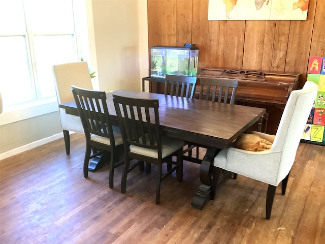 dining space featuring wood walls and dark hardwood / wood-style floors