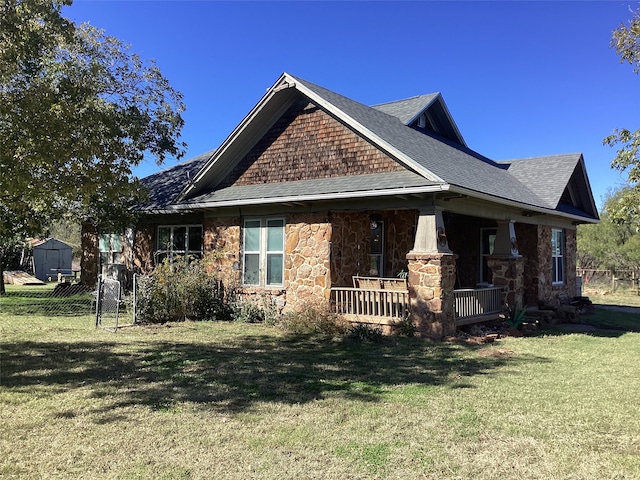 view of side of home featuring a lawn, a porch, and a storage unit