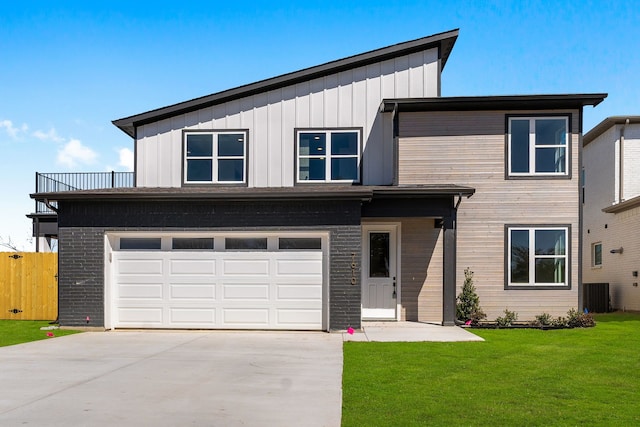 view of front of home with board and batten siding, concrete driveway, a front lawn, and a garage