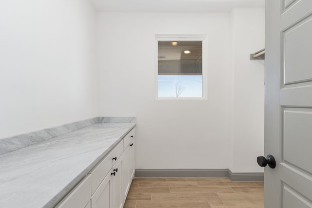 bathroom featuring wood finish floors, vanity, and baseboards