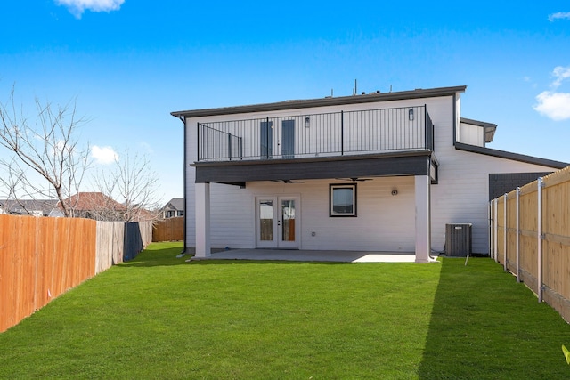 rear view of property with french doors, a lawn, ceiling fan, a balcony, and a fenced backyard