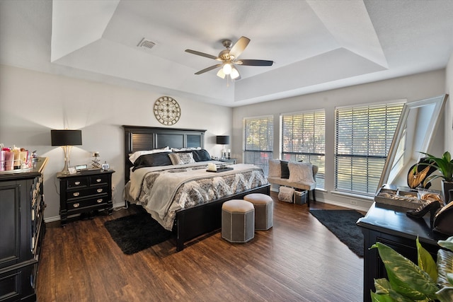 bedroom featuring a tray ceiling, ceiling fan, and dark wood-type flooring