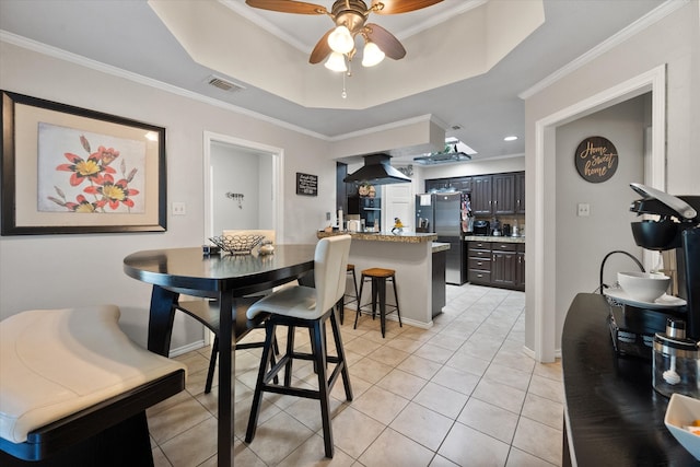 dining room featuring ceiling fan, a raised ceiling, light hardwood / wood-style flooring, crown molding, and washer and dryer