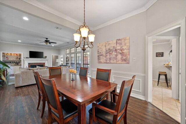 dining space with crown molding, dark wood-type flooring, and ceiling fan with notable chandelier