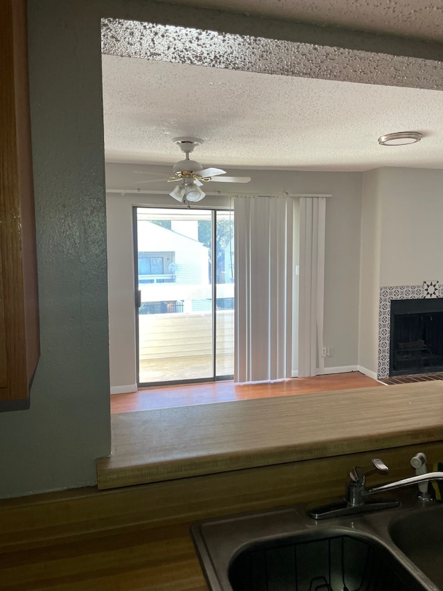 interior space featuring hardwood / wood-style flooring, ceiling fan, sink, and a tiled fireplace