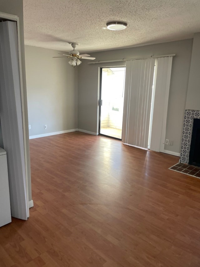 unfurnished living room with ceiling fan, a fireplace, wood-type flooring, and a textured ceiling