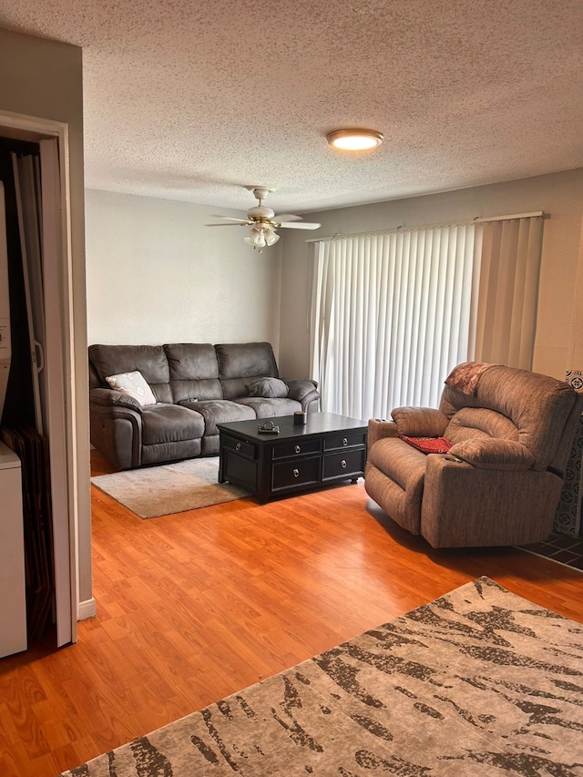 living room with ceiling fan, wood-type flooring, and a textured ceiling