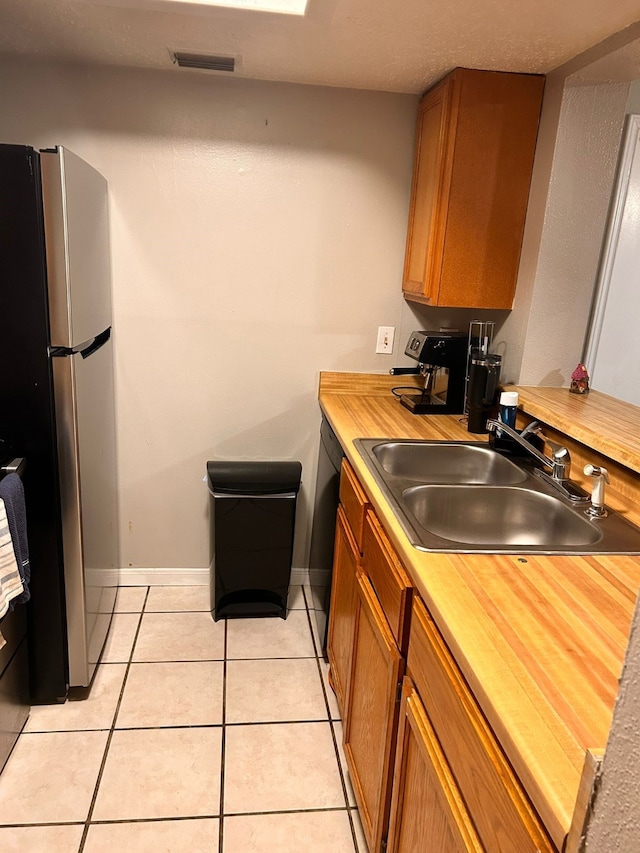 kitchen with stainless steel refrigerator, dishwasher, sink, and light tile patterned floors