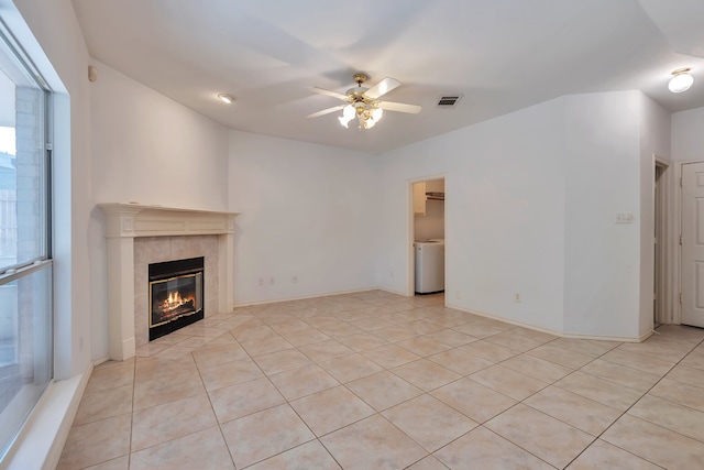 unfurnished living room with a fireplace, light tile patterned floors, washer / clothes dryer, and ceiling fan