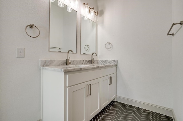 bathroom with double vanity, baseboards, and a sink