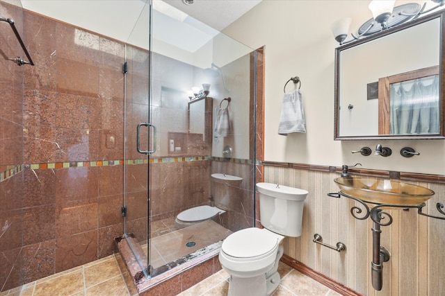 bathroom featuring tile patterned floors, toilet, and a shower with door