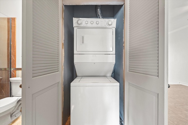 laundry room featuring stacked washer / dryer and light tile patterned flooring