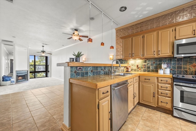 kitchen featuring kitchen peninsula, ornamental molding, stainless steel appliances, sink, and light tile patterned floors