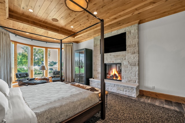 bedroom featuring hardwood / wood-style floors, beam ceiling, a stone fireplace, and wood ceiling