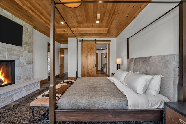 bedroom with a barn door, a fireplace, and wood ceiling