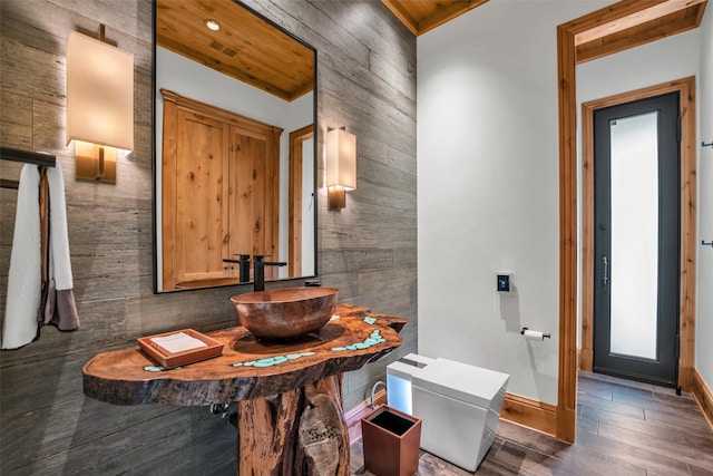 bathroom featuring wooden walls, sink, wood-type flooring, and toilet