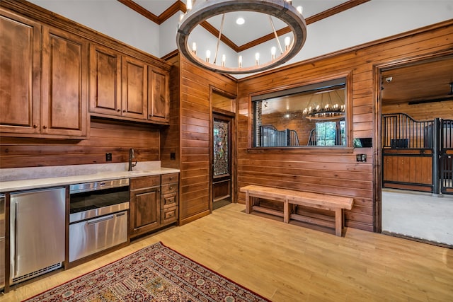 bar with stainless steel fridge, wood walls, light hardwood / wood-style floors, and ornamental molding