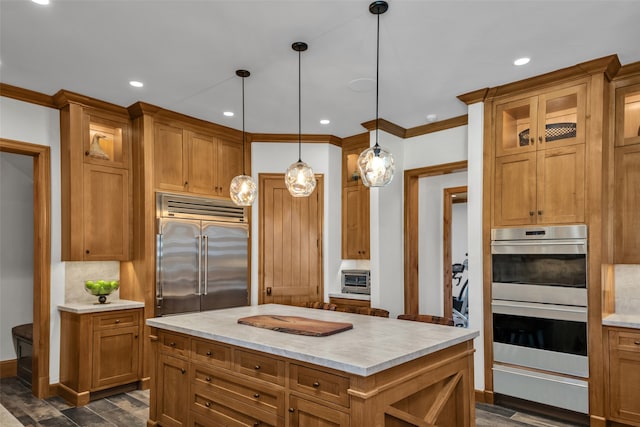 kitchen with a center island, hanging light fixtures, appliances with stainless steel finishes, and dark wood-type flooring