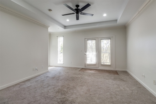 empty room with light colored carpet, a raised ceiling, ceiling fan, and ornamental molding