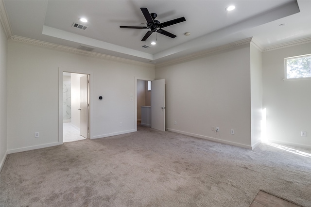 unfurnished bedroom featuring a tray ceiling, ensuite bath, ceiling fan, and ornamental molding