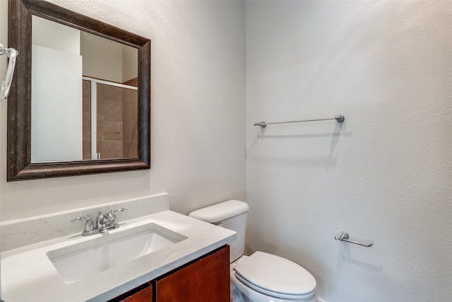 bathroom with vanity, a shower with shower door, and toilet