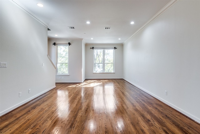 empty room with hardwood / wood-style flooring and crown molding