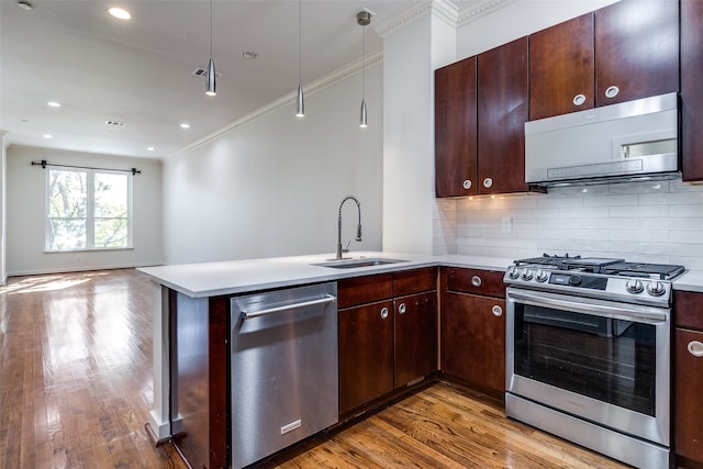 kitchen featuring kitchen peninsula, appliances with stainless steel finishes, light wood-type flooring, sink, and hanging light fixtures