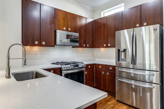 kitchen featuring sink, stainless steel appliances, light stone counters, crown molding, and light hardwood / wood-style floors