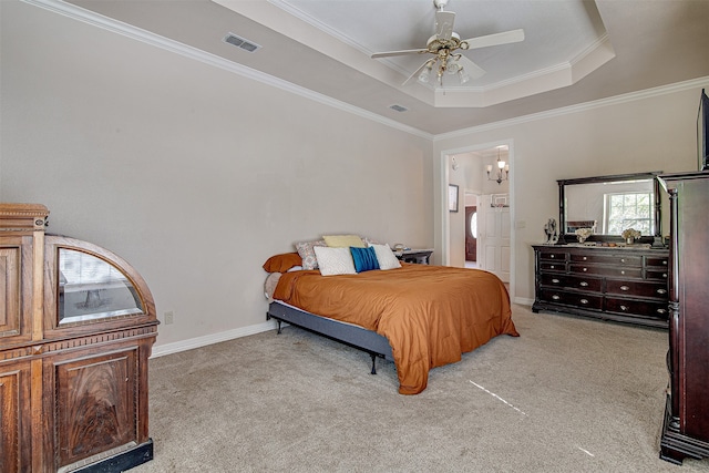 bedroom featuring ensuite bath, light colored carpet, a tray ceiling, ceiling fan, and crown molding